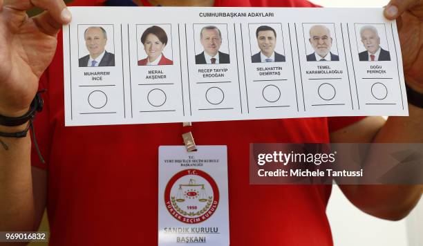 An employee shows a vote ballot paper outside of a polling station in the courtyard of the Turkish Consulate ahead of theTurkish presidential...