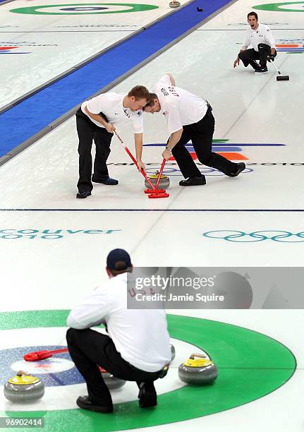 Jason Smith delivers and John Shuster calls the shot as Jeff Isaacson and John Benton of the USA sweep during the curling round robin game against...