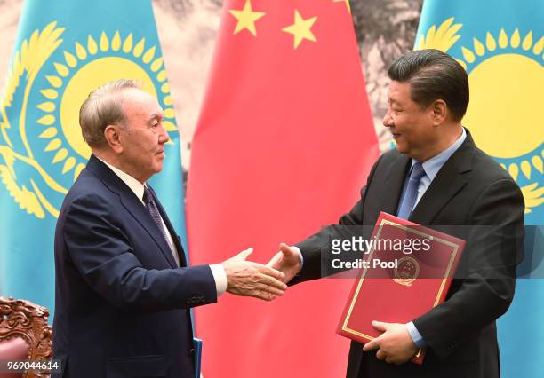 Kazakhstan's President Nursultan Nazarbayev shakes hand with Chinese President Xi Jinping during a signing ceremony in the Great Hall of the People...