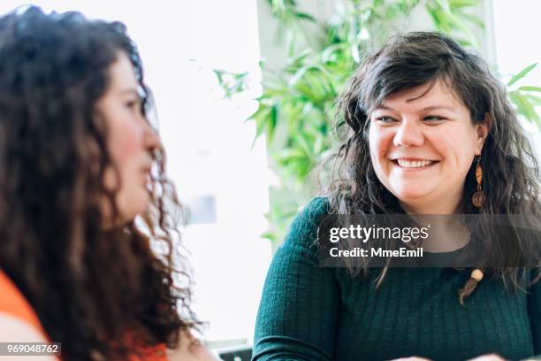 two sisters or siblings having a discussion at a table and listening to one another - sister stock pictures, royalty-free photos & images