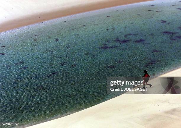 Une concurrente de l'équipe Fuji descend le long d'une dune longeant un trou d'eau douce, le 25 avril 2000 dans le désert du Lençois lors du raid Elf...