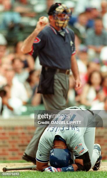 Los Angeles Dodgers' Gary Sheffield kneels over in pain after hitting himself with a foul ball, as home plate umpire Steve Rippley throws in a new...