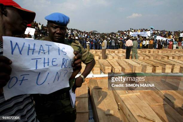 Peace keeping soldier from Senegal looks at a Burundian man holding a placard protesting against the UN for allegedly not protecting the refugees,16...