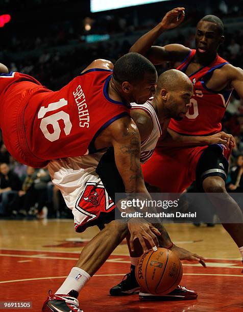 Marreese Speights of the Philadelphia 76ers falls over Taj Gibson of the Chicago Bulls while holding the jersey of teammate Jodie Meeks at the United...