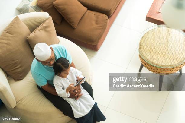 senior muslim man with his granddaughter using an e-reader - two young arabic children only indoor portrait stock pictures, royalty-free photos & images