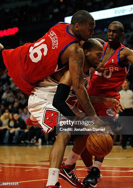 Marreese Speights of the Philadelphia 76ers falls over Taj Gibson of the Chicago Bulls while holding the jersey of teammate Jodie Meeks at the United...