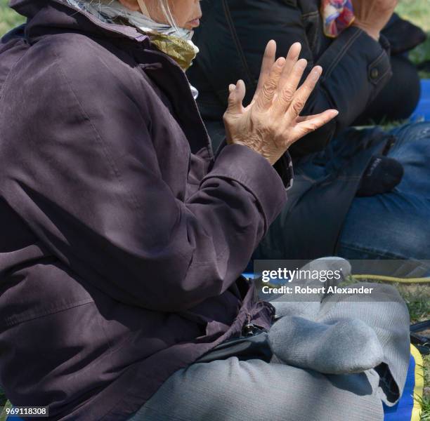 Buddhist women pray beside a Falun Dafa information display set up on the National Mall in Washington, D.C. Falun Dafa, also called Falun Gong, is a...