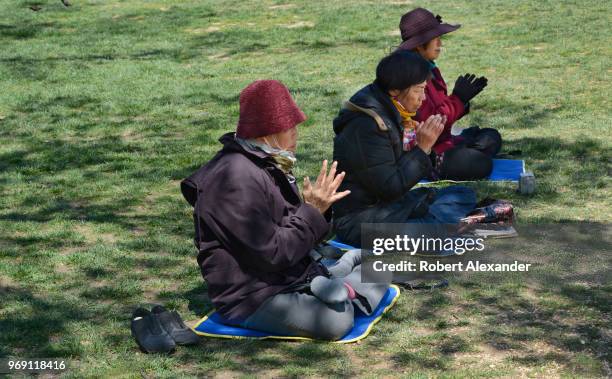 Buddhist women pray beside a Falun Dafa information display set up on the National Mall in Washington, D.C. Falun Dafa, also called Falun Gong, is a...