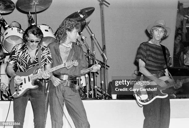View of, fore from left, British musicians Robbie Blunt, on guitar, vocalist Robert Plant, and Paul Martinez, on bass guitar, as they perform onstage...