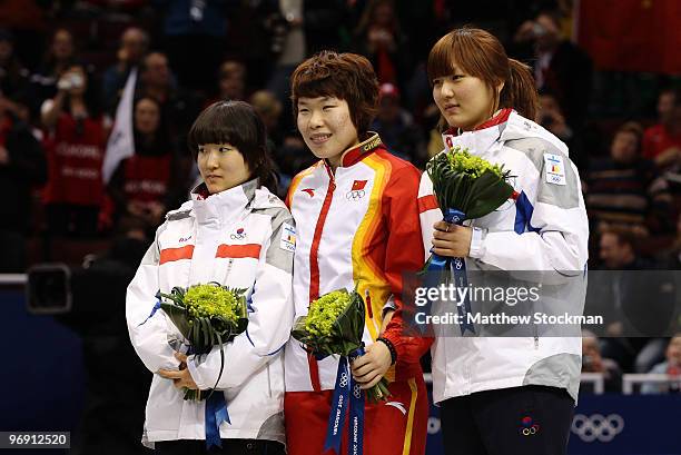Lee Eun-Byul of South Korea celebrates winning silver, Zhou Yang of China gold and Park Seung-Hi of South Korea bronze during the flower ceremony for...