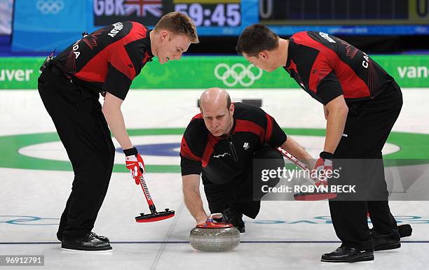 Canada skip Kevin Martin releases a stone as teammates Marc Kennedy and Ben Hebert sweep during the Canada vs Great Britain men's curling round robin...