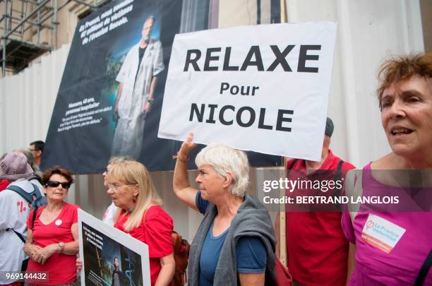 People hold banners during a protest to support Nicole Briend, an activist of the Association for the Taxation of Financial Transactions and for...