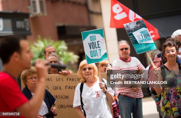 People hold banners during a protest to support Nicole Briend, an activist of the Association for the Taxation of Financial Transactions and for...