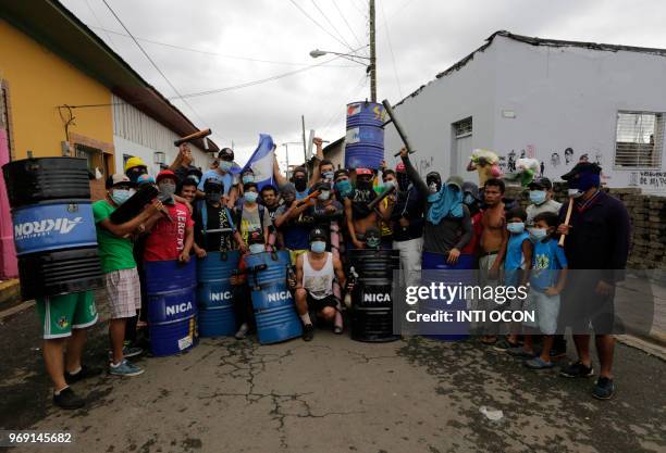 Anti-government demonstrators holding makeshift shields and mortars pose in front of a barricade during protests in the town of Masaya, 35 km from...