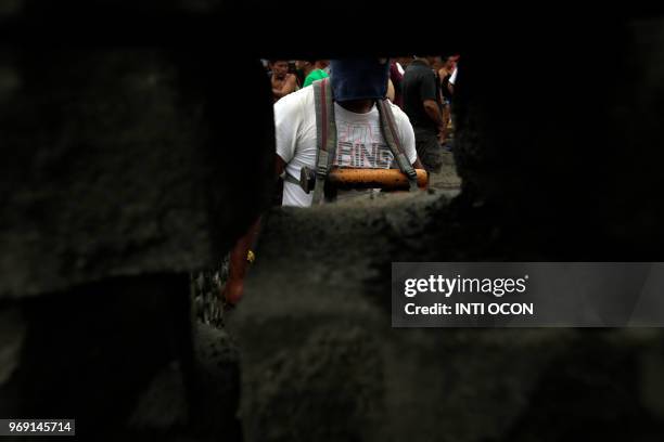 An anti-government demonstrator is seen through a barricade carrying a hand-made mortar during protests in the town of Masaya, 35 km from Managua on...