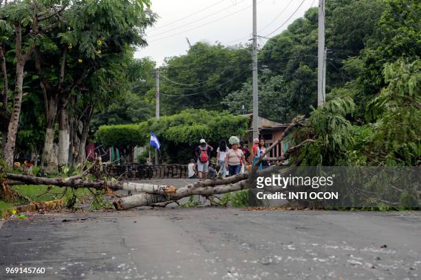Local residents walk along a blocked street in the town of Masaya, 35 km from Managua on June 5, 2018. - From little boys with skinny arms to old...