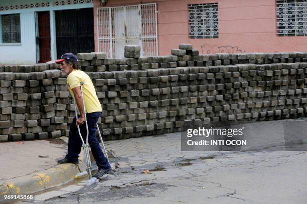 Man on crutches walks past a barricade, during anti-government protests in the town of Masaya, 35 km from Managua on June 5, 2018. - From little boys...