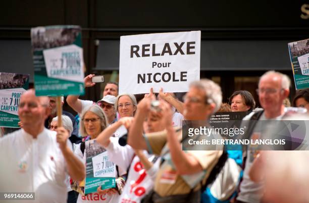 People hold banners during a protest to support Nicole Briend, an activist of the Association for the Taxation of Financial Transactions and for...
