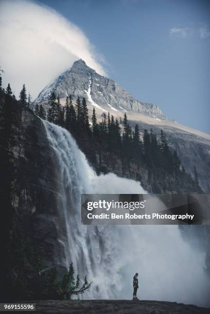 woman standing beside huge waterfall - water fall stock-fotos und bilder