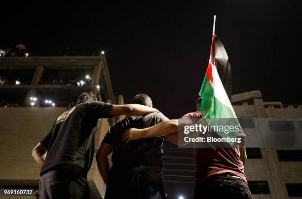 Protesters holding a Jordanian national flag look on during a demonstration against a draft income tax law near the prime minister's office in Amman,...