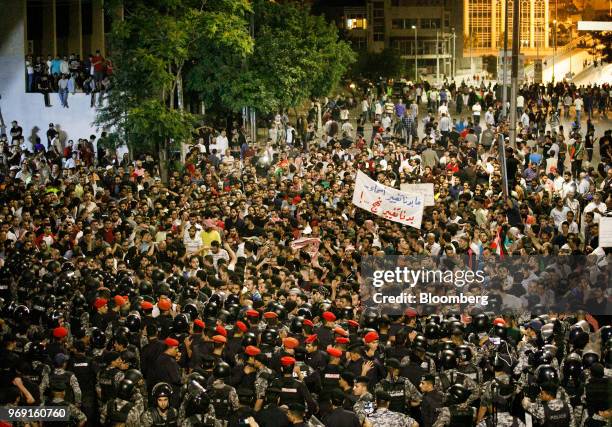 Anti riot police and security forces block the path of protesters during a demonstration against a draft income tax law near the prime minister's...