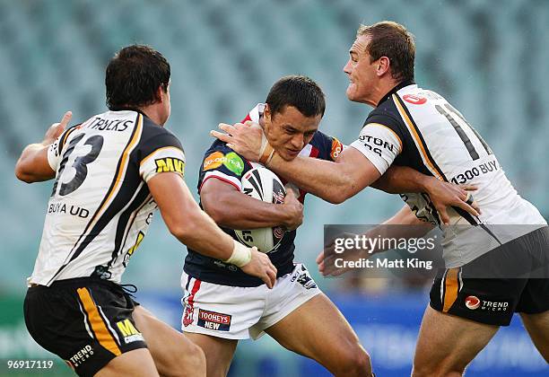 Sam Perrett of the Roosters is tackled by Gareth Ellis of the Tigers during the Foundation Cup NRL trial match between the Sydney Roosters and the...