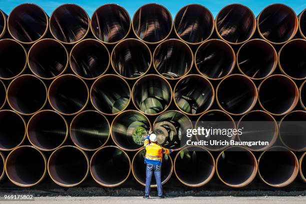 Large pipes for the Baltic Sea pipeline Nord Stream 2 on a storage area in the ferry port of Sassnitz/Neu Mukran. An employee of the responsible...