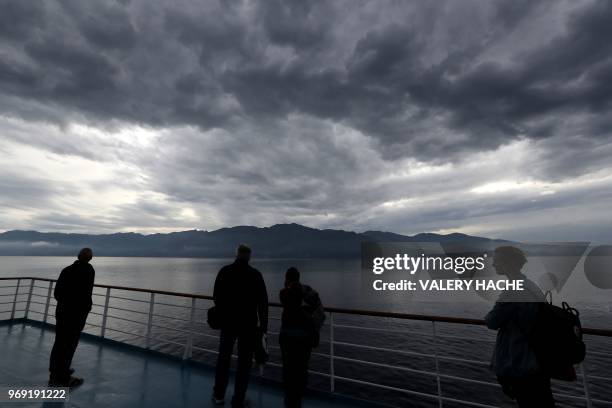 This picture taken on June 7, 2018 on board a ferry Nice-Bastia shows passengers looking at Cap Corse, on the French Mediterranean sea island of...