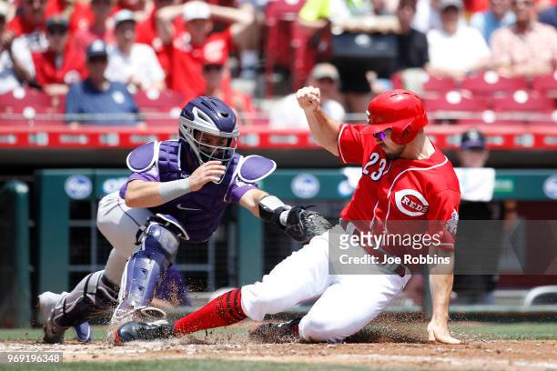 Adam Duvall of the Cincinnati Reds slides home with a run ahead of the tag by Tony Wolters of the Colorado Rockies in the second inning at Great...