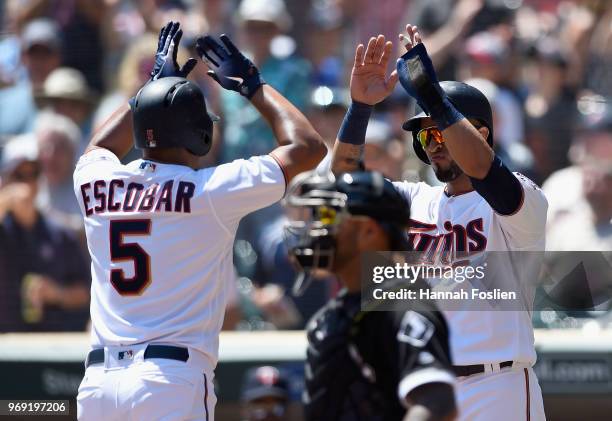 Eddie Rosario of the Minnesota Twins congratulates teammate Eduardo Escobar on a two-run home run as Omar Narvaez against the Chicago White Sox in...