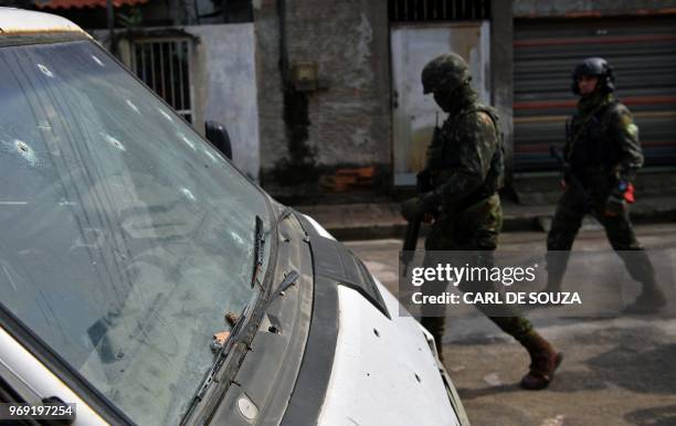 Soldiers walk past a van with bullet holes in its windscreen, during an operation at "Cidade de Deus" favela in Rio de Janeiro, Brazil on June 07,...