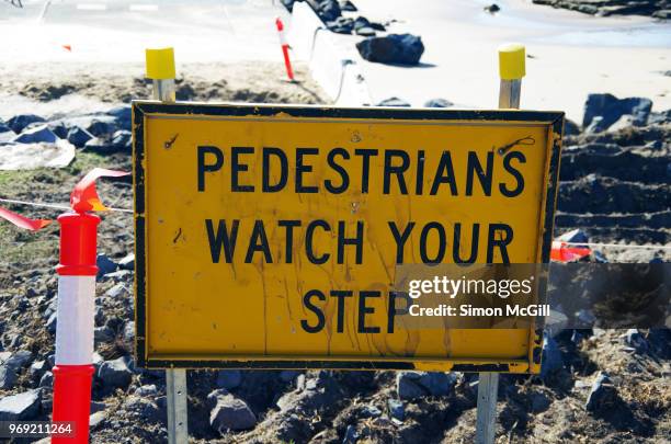 'pedestrians watch your step' sign near a construction site near a beach - trip hazard stock pictures, royalty-free photos & images