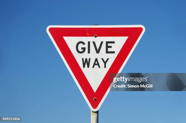 give way sign against a clear blue sky - give way - fotografias e filmes do acervo