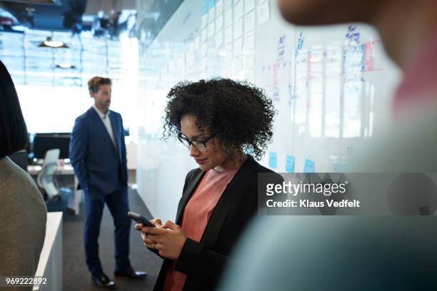 businesswoman looking at smartphone inside creative office - call conference stock-fotos und bilder