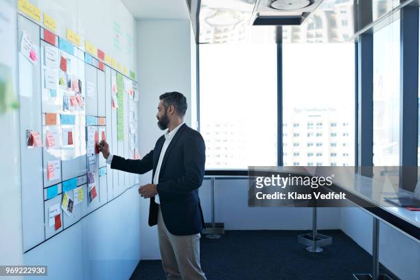 businessman sticking note on whiteboard in office - 2018 calendar foto e immagini stock