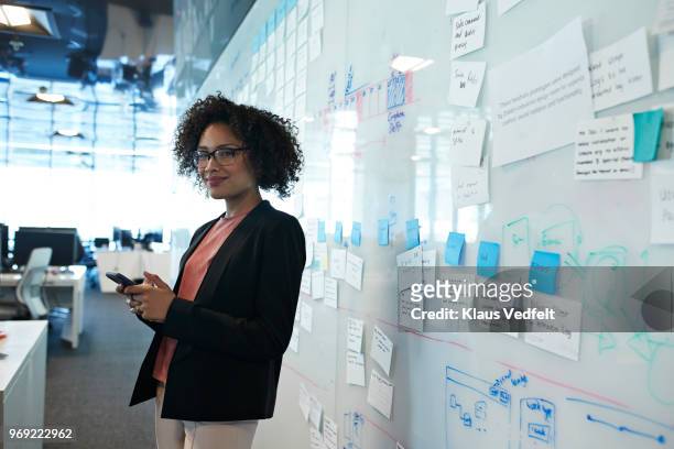 portrait of cool businesswoman holding smartphone - woman whiteboard fotografías e imágenes de stock