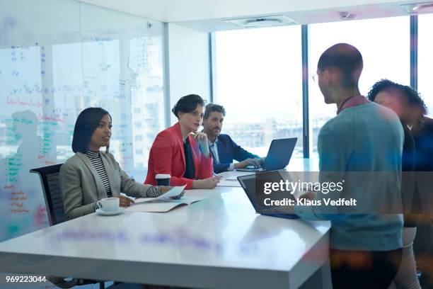 businesspeople having standing meeting at creative agency - roter anzug stock-fotos und bilder