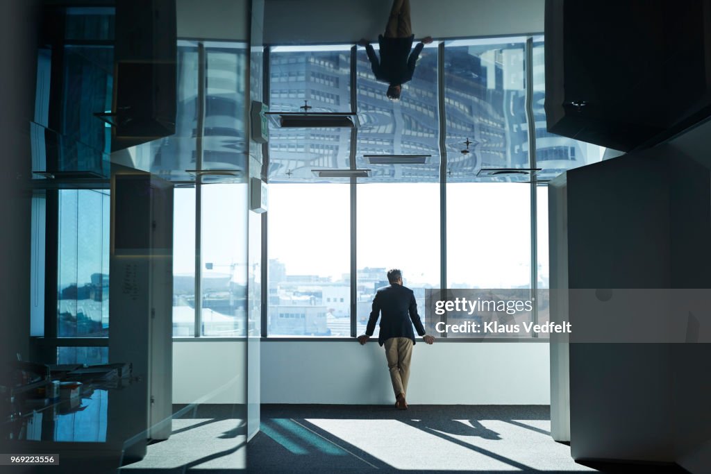 Businessman looking out of window from inside of big office building