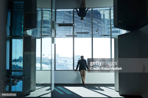 businessman looking out of window from inside of big office building - glass shadow stockfoto's en -beelden