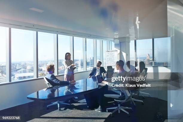 young entrepreneur presenting project in exclusive boardroom - multi ethnic business people having discussion at table in board room stock pictures, royalty-free photos & images