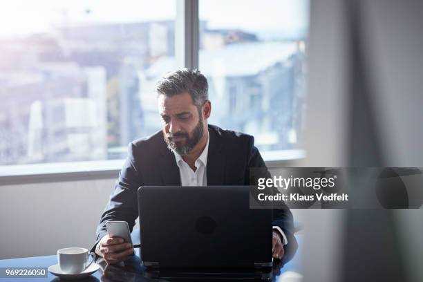 businessman with laptop, tjecking phone - businessman working on a laptop with a coffee stock pictures, royalty-free photos & images
