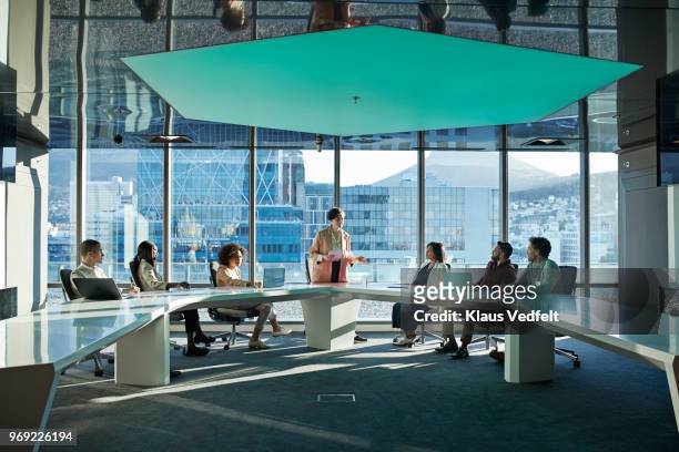businesspeople having meeting in large futuristic board room - affari finanza e industria foto e immagini stock