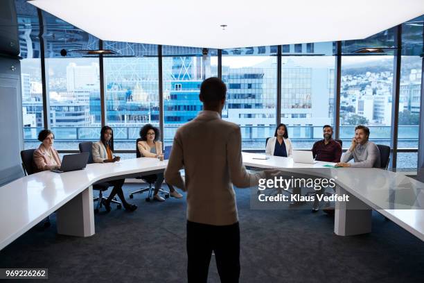 businesspeople having meeting in large futuristic board room - men and women in a large group listening stock pictures, royalty-free photos & images