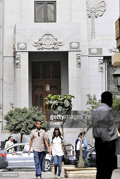 An Egyptian couple walk past central Cairo's Shaar Hashamayim synagogue following a molotov cocktail attack on the historic Jewish temple which...