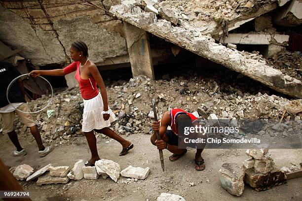 Steps away from still-buried corpses, young Haitians use steel bars and metal wire to measure and mark-off their new shacks in the collapsed Marche...