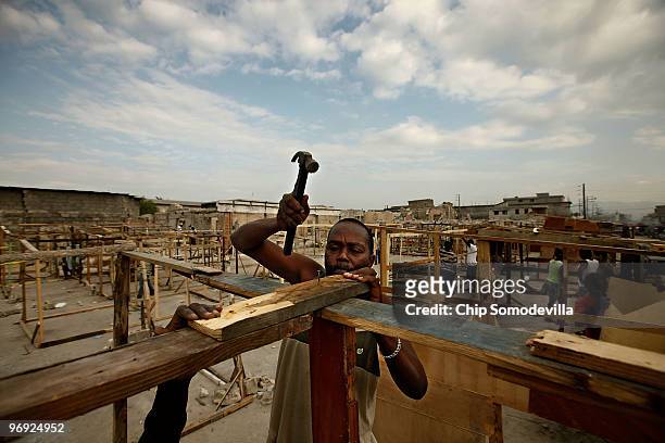 Paul Marie helps a friend build a shack on a concrete slab where the collapsed Marche Tete Boeuf market once stood along the Grand Rue, one of the...