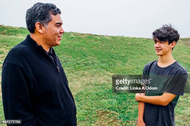 father and teenage son talking in park - new orleans people stock pictures, royalty-free photos & images