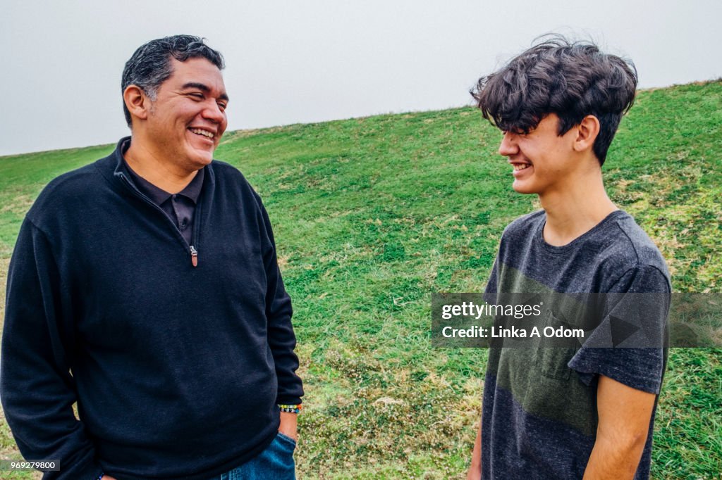 Father and Teenage Son talking in Park