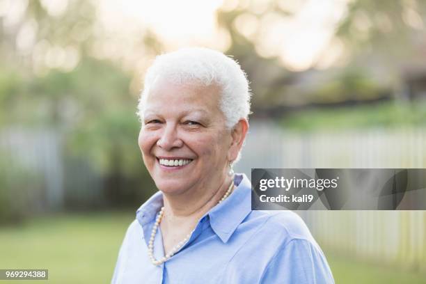 senior hispanic woman standing in back yard - pearl earring stock pictures, royalty-free photos & images