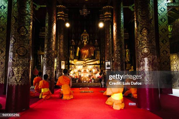 buddhist monks pray inside wat mai suwannaphumaham - laotiaanse cultuur stockfoto's en -beelden